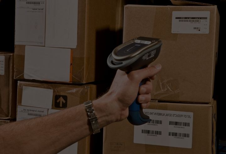 Warehouse worker pointing a barcode scanner at a barcode on a box